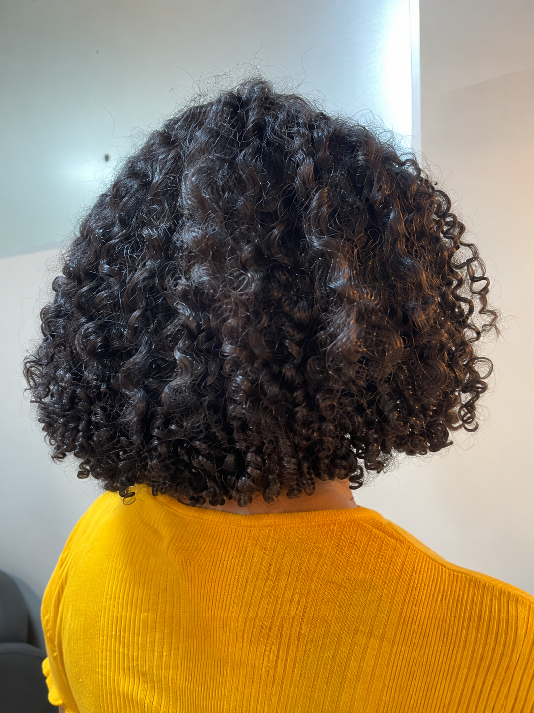 Depois do protocolo em cabelo cacheado da cliente de blusa laranja